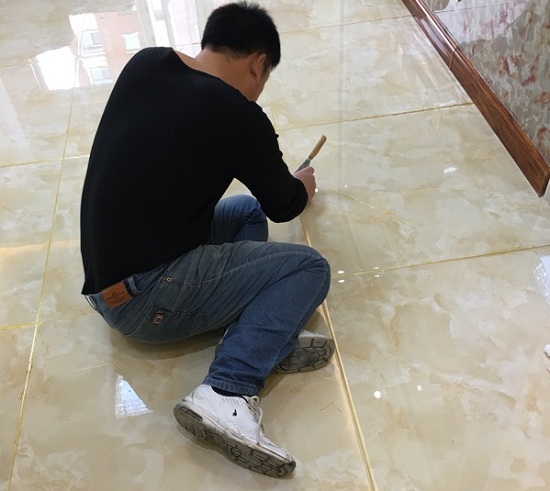 王先生正在給客廳瓷磚美縫